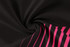 A black fabric with pink stripes, showcasing a smooth, swirling texture. The material appears soft and flexible.