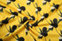 A vibrant yellow fabric with black and white floral patterns, featuring a swirling design.