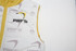 A white and yellow puffer vest with a removable hood and branding, featuring a sleeveless design.