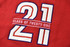 A red fabric with large white and blue embroidered numbers "21" and the text "CLASS OF TWENTY-ONE" underneath.