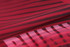 A close-up of a red sports uniform featuring bold black stripes and a branding logo.