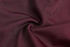 A smooth, maroon fabric with a slight sheen, twisted in a circular pattern.