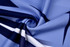 A swirl of fabric featuring shades of blue with black and white patterns, ideal for swimwear. It has a branding logo.