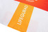 A swimming suit in white, orange, and yellow with a logo and the word "LIFEGUARD" prominently displayed.