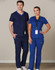 A man and woman wear solid colour scrub tops and pants in navy and blue, with badges and a logo present.