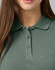 A close-up of a women's cotton stretch polo shirt in a muted green shade, featuring a classic collar and button detail.