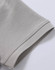 A close-up of a light grey polo shirt's sleeve, showcasing the pique texture and stitch detailing.