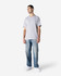 A grey adult T-shirt with a relaxed fit, paired with blue jeans and white shoes. The shirt features a logo.