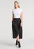 A woman wearing a black maxi skirt paired with a white T-shirt and black ankle boots, featuring a front slit and pockets.