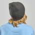 A dark grey beanie viewed from the back, worn by a person with wavy blonde hair, with a blue sweatshirt visible.