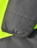 A close-up of a two-tone safety jacket featuring fluorescent yellow and charcoal grey fabric. It has a textured finish and elastic cuffs.