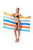 A woman in a black bikini holds a colourful striped beach towel in blue, orange, yellow, and white.