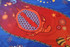 A colourful hand towel featuring intricate patterns of a turtle, starfish, and abstract designs in red and blue.