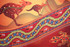 A vibrant beach towel featuring red and orange patterns with kangaroos and a snake design, and a decorative border.