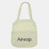 A light cream cotton shopping tote with a logo on the front and two handles.