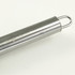 A stainless steel BBQ tool with a looped handle, featuring a subtle logo on its surface.