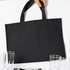 A black picnic backpack with sturdy handles, placed near glasses and tableware. It has a simple, minimalistic design.