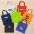 A collection of eight tote bags in various colours, including white, green, orange, blue, and black, with different logos.
