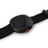A black smart watch with a round face and a textured orange button on the side. The strap is made of a flexible material.