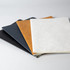 A set of four notebooks in black, dark blue, tan, and white, featuring a textured cover and no visible branding.