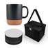 A black coffee mug with a cork base, a black speaker, and a black carrying bag with a strap.