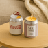 A mini candle designed like a soda can, featuring silver and pink colours with a flame on top.