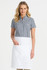 A short sleeve button-up shirt in black and white gingham pattern, paired with a white apron. The model is smiling.