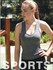 A model wearing a grey sports tank top poses outdoors, with a blurred natural background. The image features a logo.
