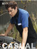 A blue and black button-up shirt featuring a pocket and a logo, worn by a man working on a car engine.