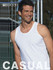 A man smiles while wearing a white cotton singlet, standing against a fence background. The singlet has a logo.