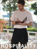 A man wears a black cotton drill quarter apron with a pocket, holding a notebook in an outdoor setting.