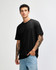 A black sueded unisex short sleeve T-shirt displayed on a model with tattoos, paired with light blue jeans.