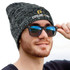 A knit beanie in heather gray featuring a gold logo, worn by a person wearing black sunglasses.