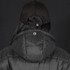 A black puffer jacket with a hood, worn by a person wearing a black cap, featuring a logo on the back.