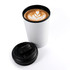 A white reusable coffee cup with a black lid, featuring a latte with a heart-shaped design.