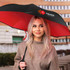 A black and red inverted umbrella with a logo, held by a woman with long hair, set against a building backdrop.