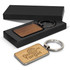 A rectangular key ring with a wooden finish, presented in a black gift box. Features a logo on one side.