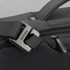 A close-up of a black anti-theft backpack featuring a sturdy buckle and zipper detail. It has a sleek, modern design.