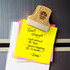 A bamboo clip holding several colourful sticky notes on a fridge, featuring a smooth finish and a logo.