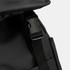 A close-up of a black soft-touch backpack featuring a clip and adjustable strap. The material appears durable.