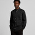 A black denim wash shirt with a button-up front and a chest pocket, worn by a model.