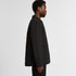 A black quilted puffer jacket viewed from the side, featuring a button-down front and a subtle logo.