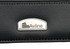 A black travel wallet featuring a branded metal logo. The wallet has a textured finish and sleek design.