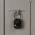 A black TSA lock secured to a grey locker, featuring a combination dial and a small logo.