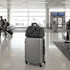 A grey High Sierra travel duffel rests on top of a silver suitcase in an airport terminal. It features a logo.