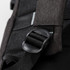 A close-up of a black backpack strap buckle with textured fabric in the background. The backpack has a logo.