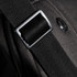 A close-up of a black strap buckle on a bag, featuring a textured fabric and a circular logo.