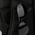 A black backpack with a mesh pocket and a pair of black sunglasses hanging from it. It features a logo.