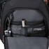 An inner pocket of a black backpack featuring compartments for a pen, keys, and a small device.
