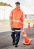 A heavy-duty waterproof jacket in fluorescent orange with reflective strips, worn by a model in blue work pants.